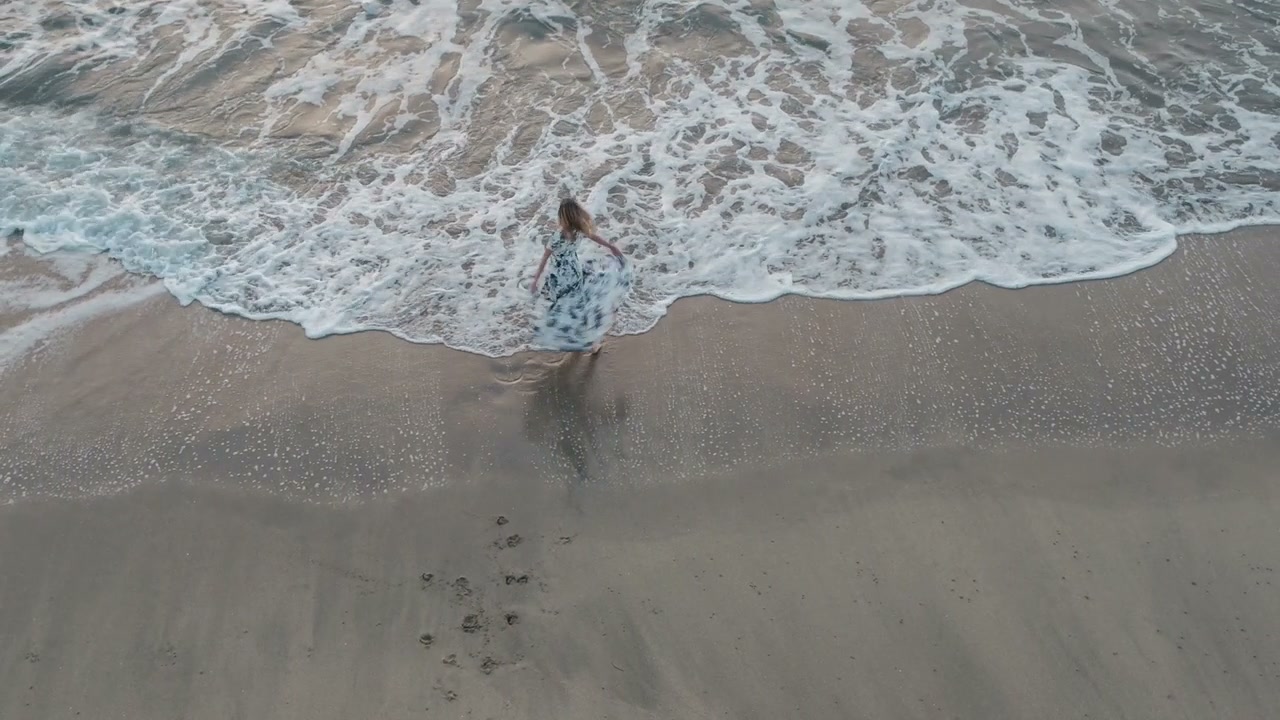 Frau geht leichtfüßig am Strand – Symbolbild